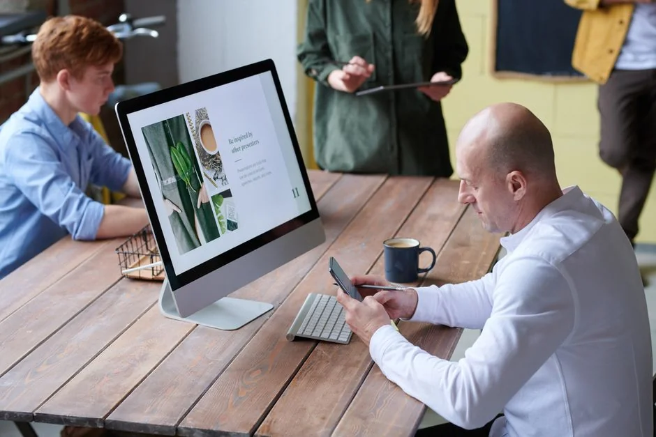 Un photographe travaille dans un environnement créatif avec un ordinateur portable et une tablette Wacom, concentré sur la retouche photo en intérieur.